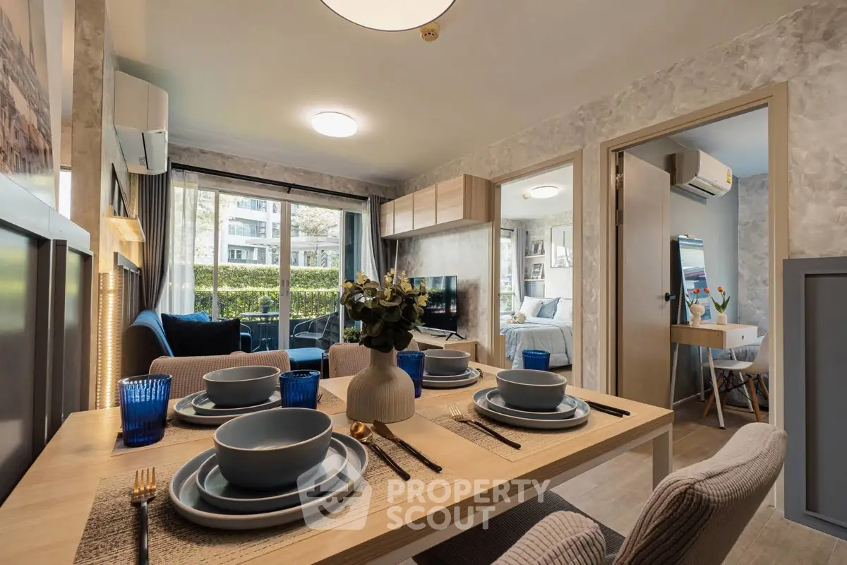 Modern dining area with elegant table setting in a cozy apartment, featuring a view into the living room and bedroom.