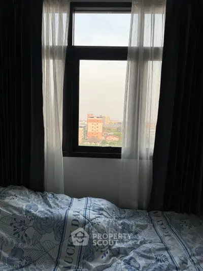 Cozy bedroom with city view through window, featuring elegant curtains and stylish bedding.