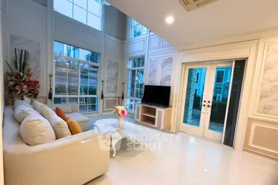 Luxurious living room with high ceilings, elegant decor, and large windows offering natural light.