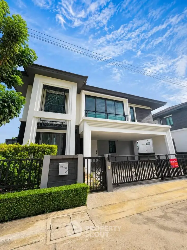 Modern two-story house with sleek design and large windows in a suburban neighborhood.