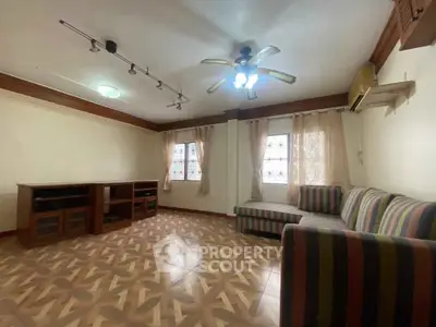 Spacious living room with stylish striped sofa and ceiling fan, featuring elegant patterned flooring.