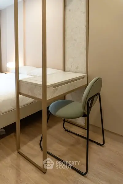 Modern bedroom with stylish chair and desk, featuring elegant wood flooring and soft lighting.