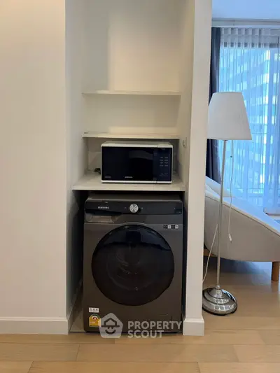 Modern apartment interior with washing machine and microwave in a cozy living space.