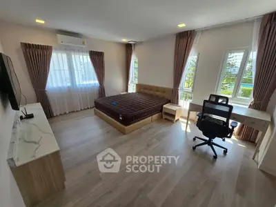 Spacious bedroom with modern furnishings and large windows offering natural light.