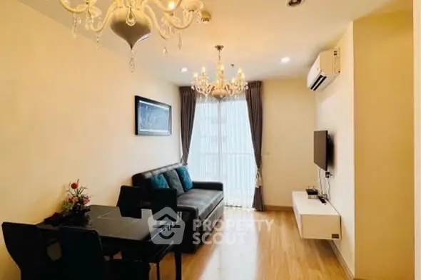 Elegant living room with chandelier, sofa, and wall-mounted TV in modern apartment.