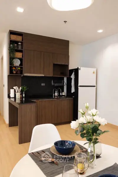 Modern kitchen with dark wood cabinets and sleek appliances in a cozy apartment setting.