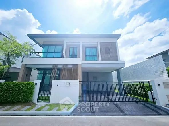 Modern two-story house with sleek design and spacious driveway under a bright blue sky.