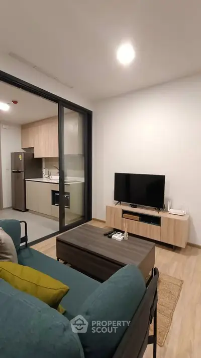 Modern living room with open kitchen, featuring sleek furniture and contemporary design.