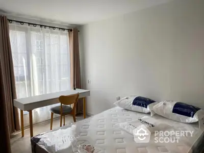 Bright bedroom with large window, modern desk, and comfortable bed in stylish apartment.