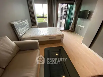 Modern bedroom with large window and balcony access, featuring a cozy sofa and sleek glass coffee table.