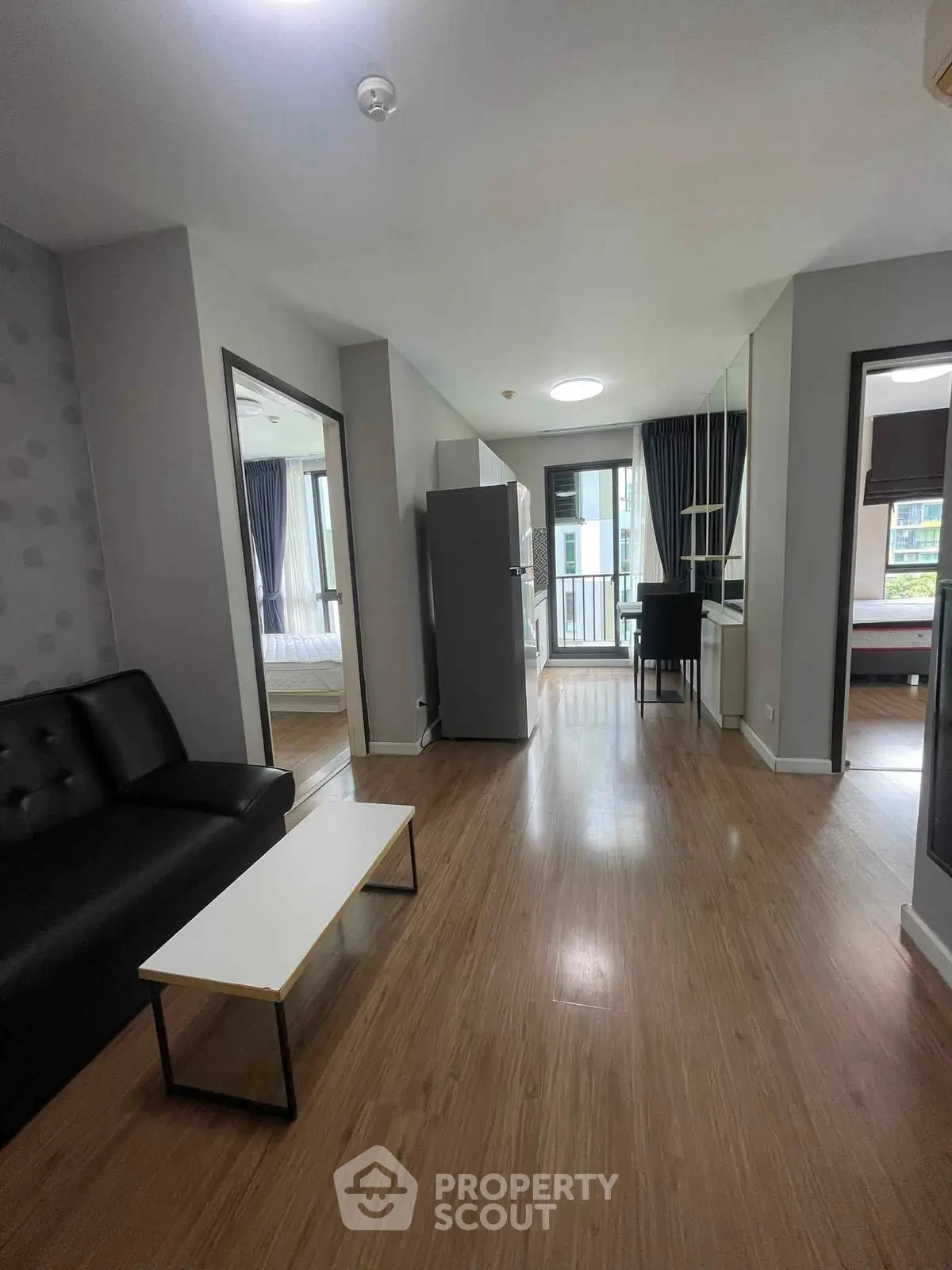 Modern apartment interior with open layout, featuring a cozy living area and a view of the balcony.