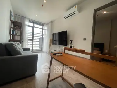Modern living room with sleek furniture and large window offering city view.