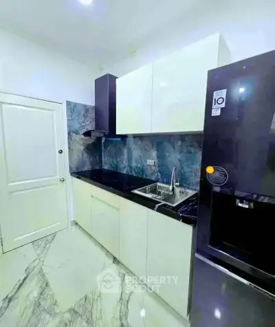 Modern kitchen with sleek cabinets and marble flooring, featuring a built-in sink and stylish backsplash.