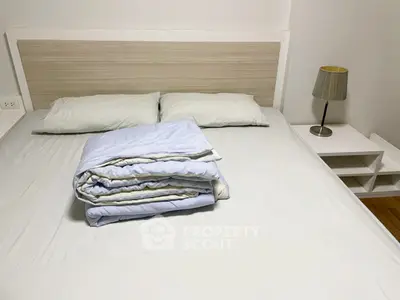 Cozy bedroom with neatly arranged bed and modern lamp, perfect for relaxation.