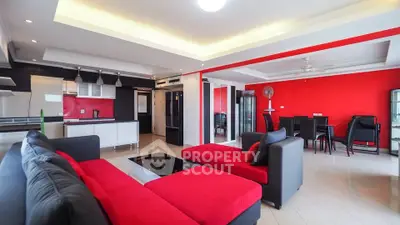 Spacious modern living room with open kitchen and vibrant red accents