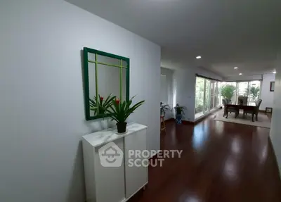 Spacious hallway with wooden flooring and modern decor leading to a bright living area with garden view.
