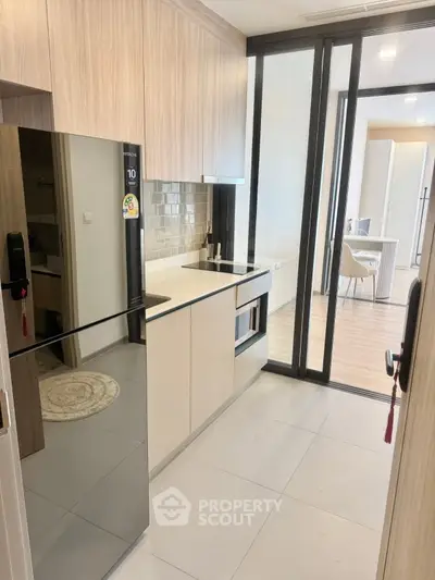 Modern kitchen with sleek appliances and open layout leading to dining area.
