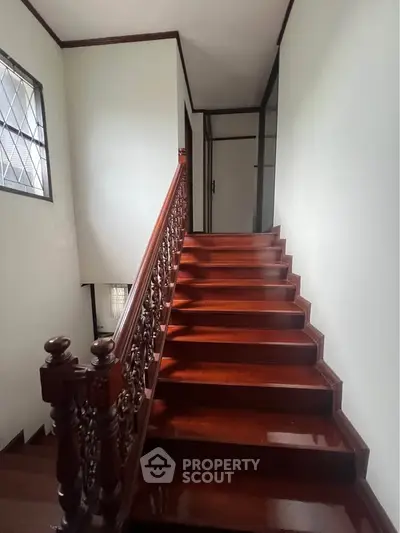 Elegant wooden staircase with intricate railing in a well-lit home interior
