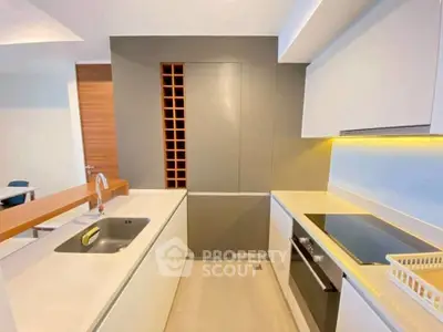 Modern kitchen with sleek design, featuring built-in wine rack and electric stove.