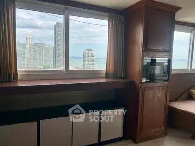 Spacious room with stunning city and ocean view, featuring large windows and elegant wooden cabinetry.