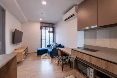 Modern living room with open kitchen, featuring sleek furniture and natural light.