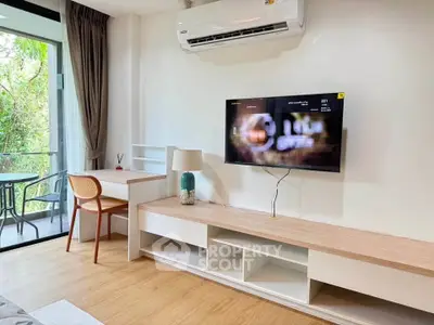 Modern living room with balcony view, featuring sleek furniture and wall-mounted TV.
