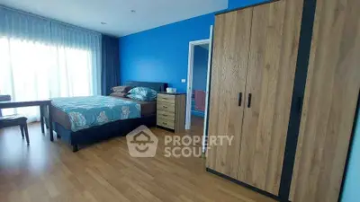 Spacious bedroom with modern furnishings and large window for natural light.