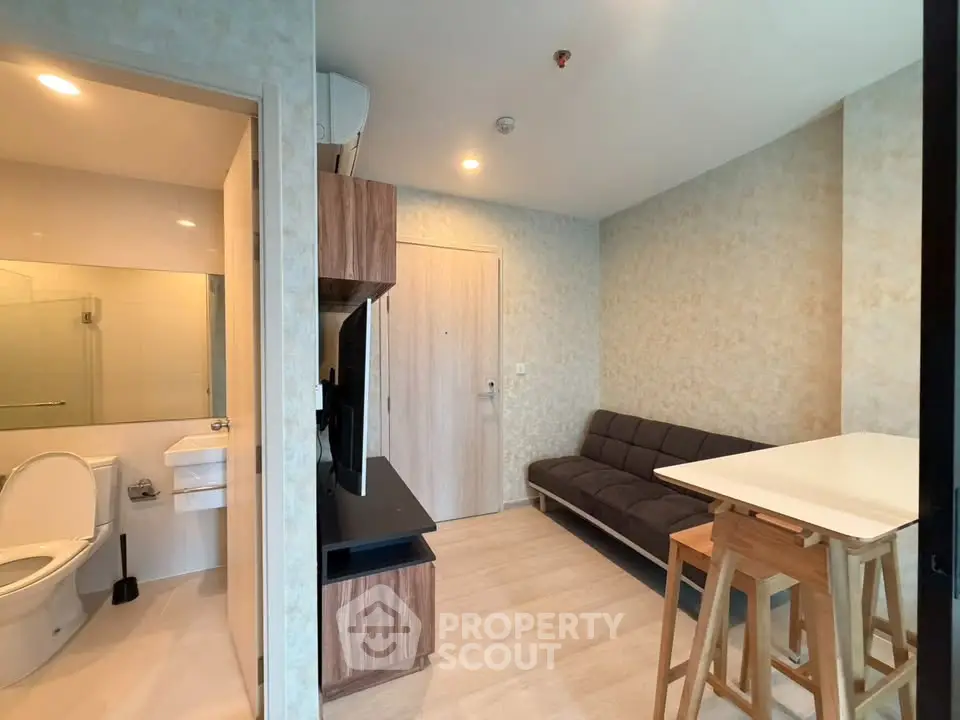 Modern apartment interior with cozy living area and adjacent bathroom, featuring sleek design and neutral tones.