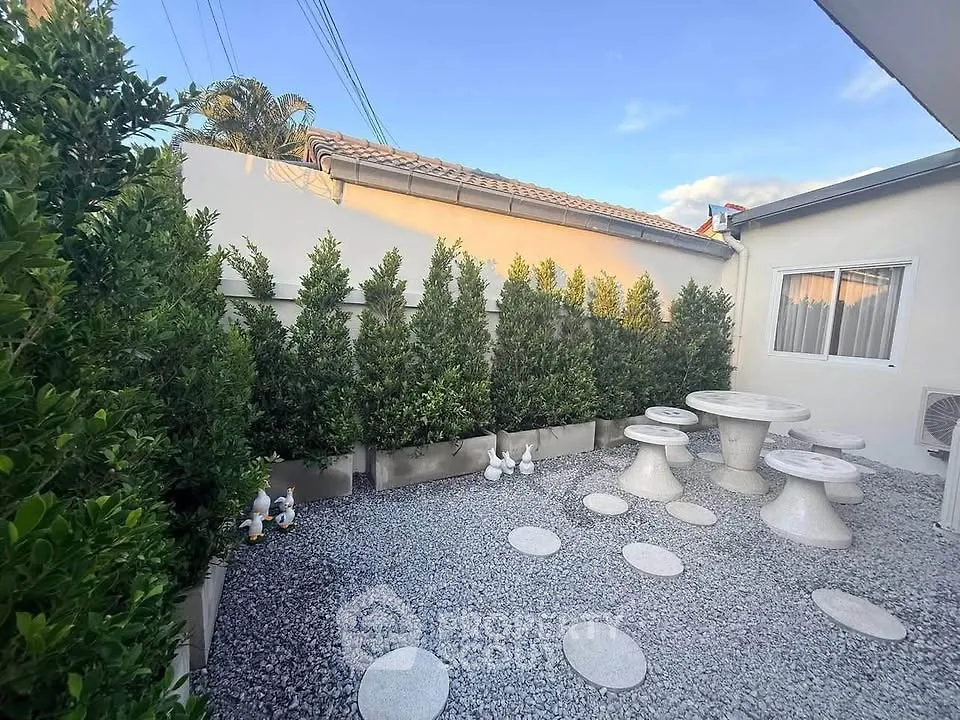 Charming outdoor garden area with stone seating and lush greenery, perfect for relaxation and entertainment.