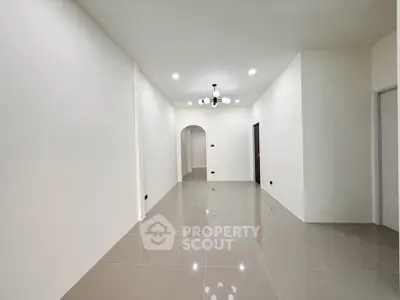 Spacious modern hallway with glossy tiled flooring and elegant lighting.