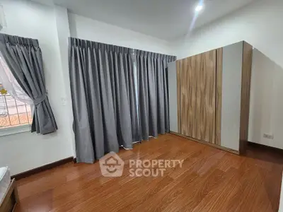 Spacious bedroom with wooden flooring and large wardrobe, perfect for modern living.