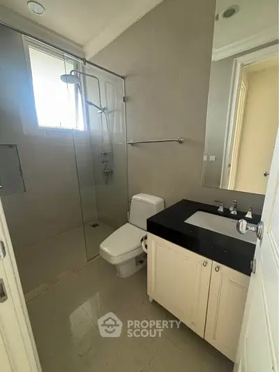 Modern bathroom with glass shower and sleek vanity in a bright, minimalist design.