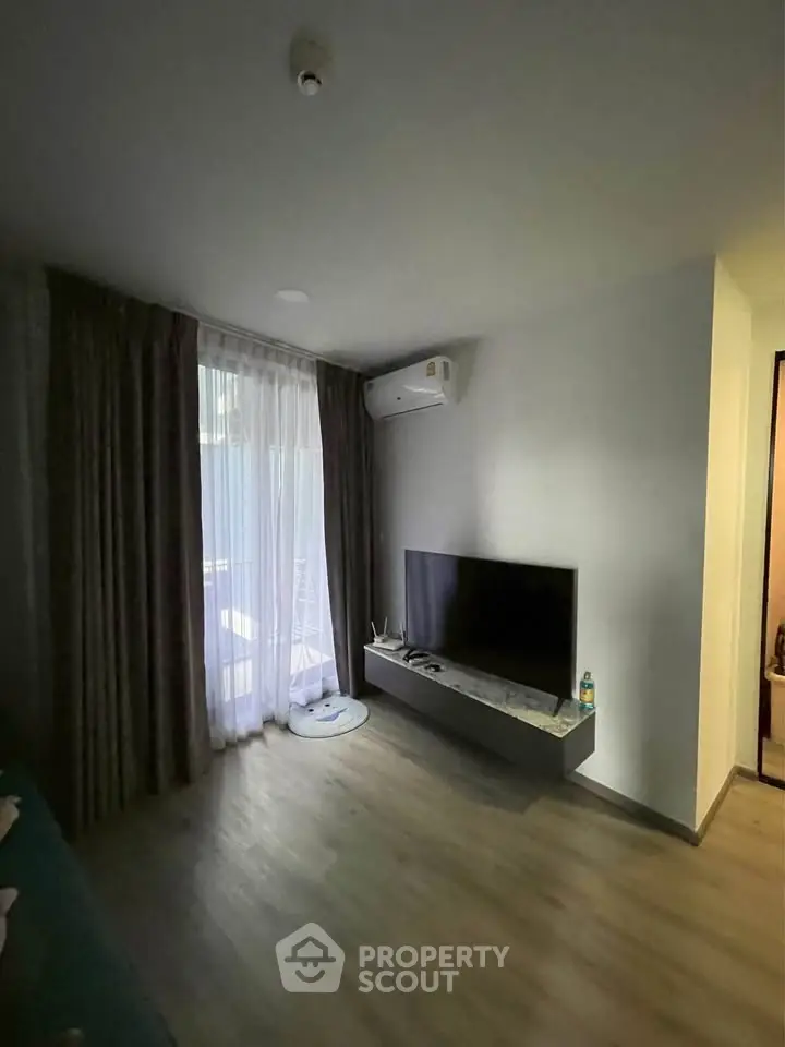Modern living room with sleek TV setup and natural light from large window.