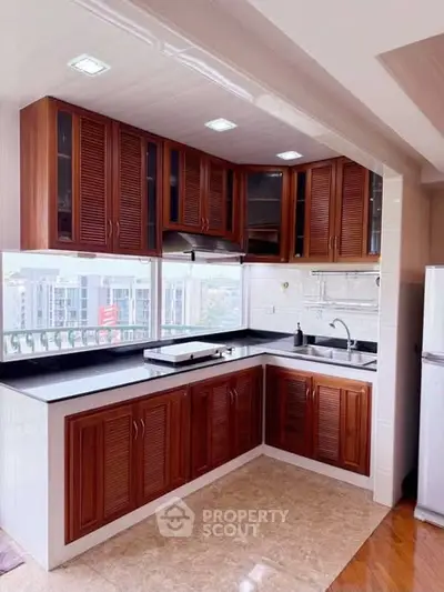 Modern kitchen with wooden cabinets and large window offering city view