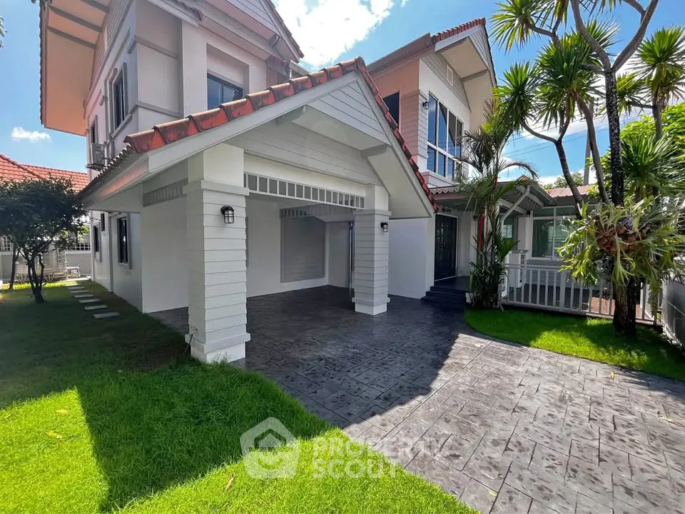 Charming two-story house with lush garden and spacious driveway in sunny setting.