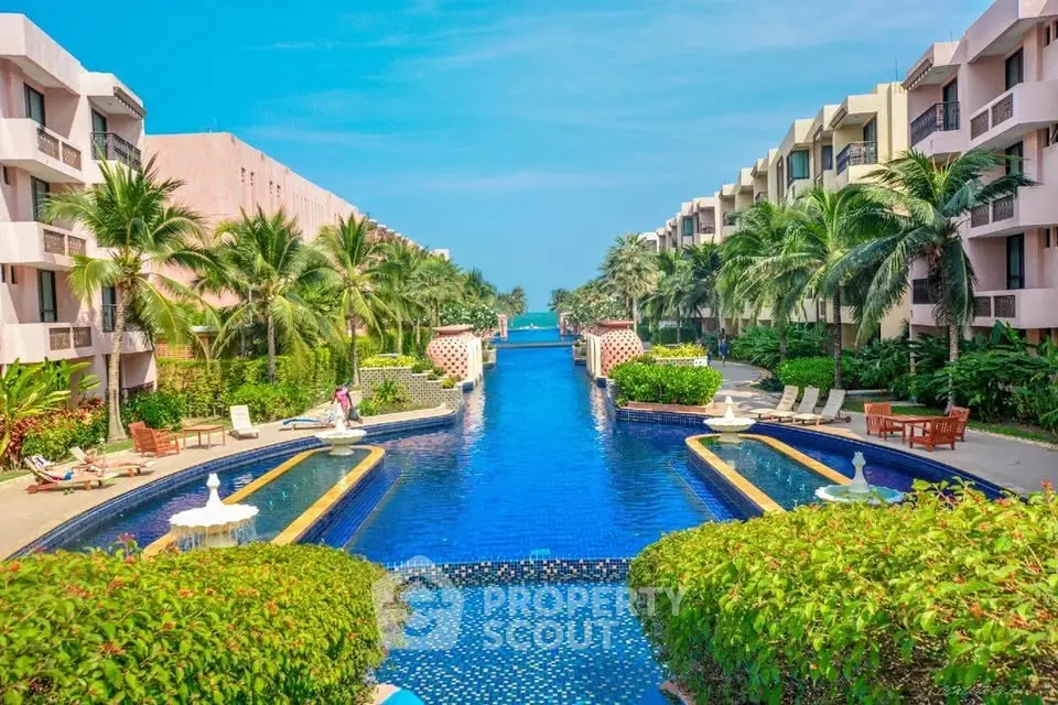 Luxurious resort-style pool with lush greenery and modern apartment buildings, perfect for relaxation and leisure.
