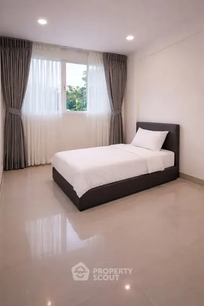 Minimalist bedroom with single bed and large window, perfect for serene living.