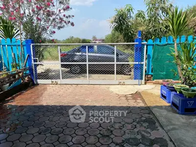 Charming garden entrance with paved pathway and vibrant greenery, perfect for serene outdoor living.