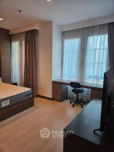 Modern bedroom with large windows and study desk, perfect for urban living.