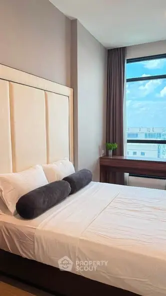 Modern bedroom with large window and stylish decor, offering a bright and inviting atmosphere.