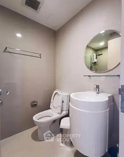 Modern bathroom with sleek fixtures and round mirror, ideal for contemporary living.