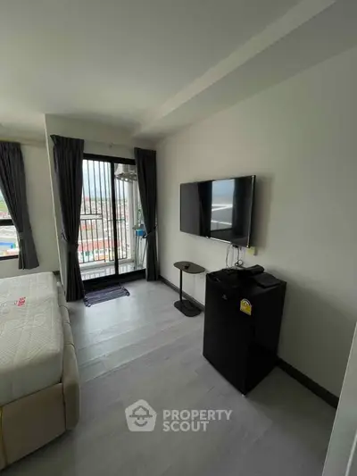 Modern bedroom with balcony view, wall-mounted TV, and sleek flooring.