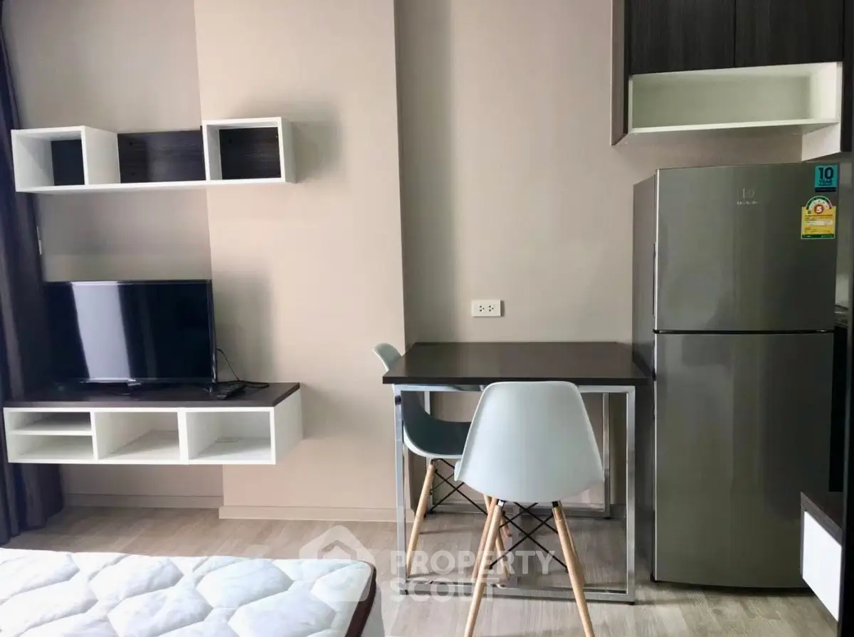 Modern studio apartment with sleek furniture and stainless steel fridge, perfect for urban living.