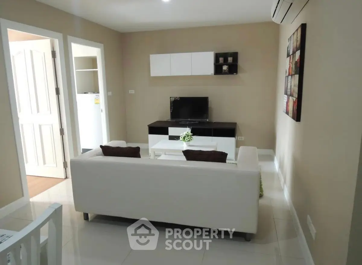 Modern living room with sleek furniture and wall-mounted TV in a cozy apartment.