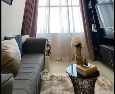 Cozy living room with plush sofa, elegant decor, and natural light through sheer curtains.