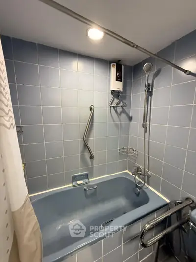Cozy bathroom with blue tiles and bathtub, featuring a shower and water heater for ultimate relaxation.