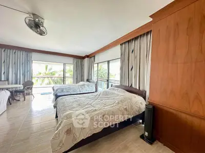 Spacious bedroom with large windows and twin beds, offering a serene view of lush greenery.