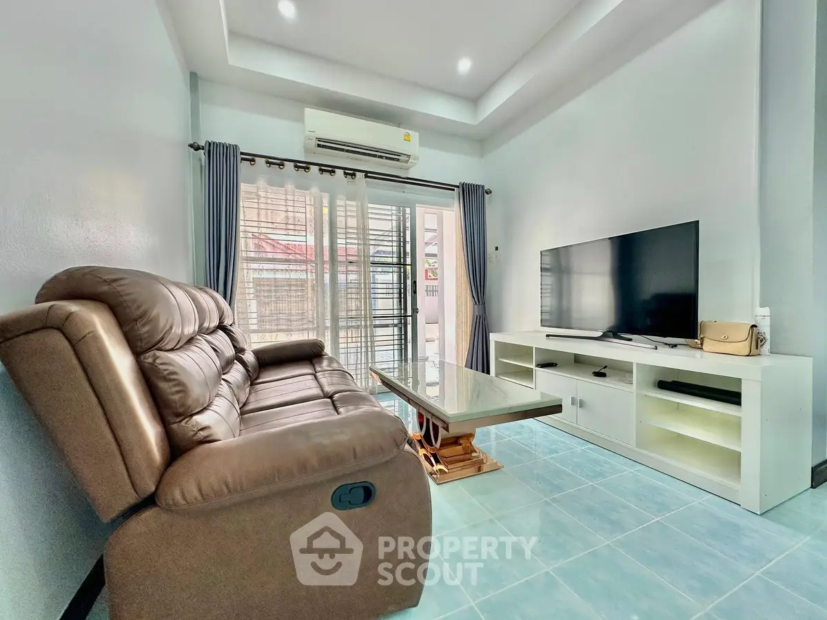 Modern living room with leather sofa, TV, and air conditioning