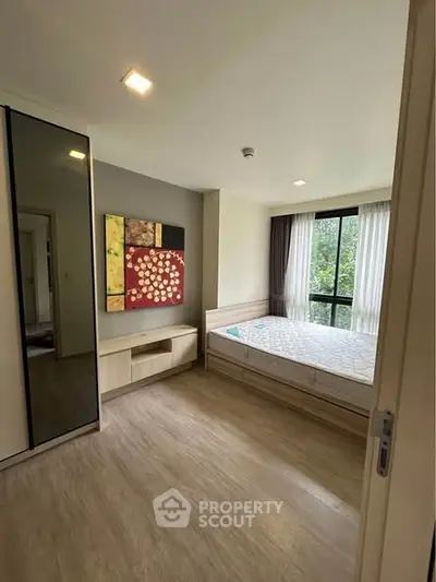 Modern bedroom with large window and stylish decor in a cozy apartment.