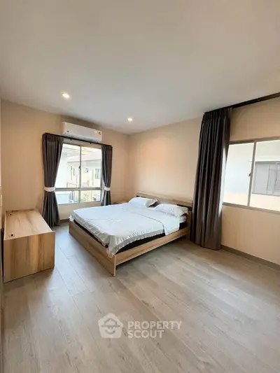 Spacious bedroom with modern decor and large window for natural light